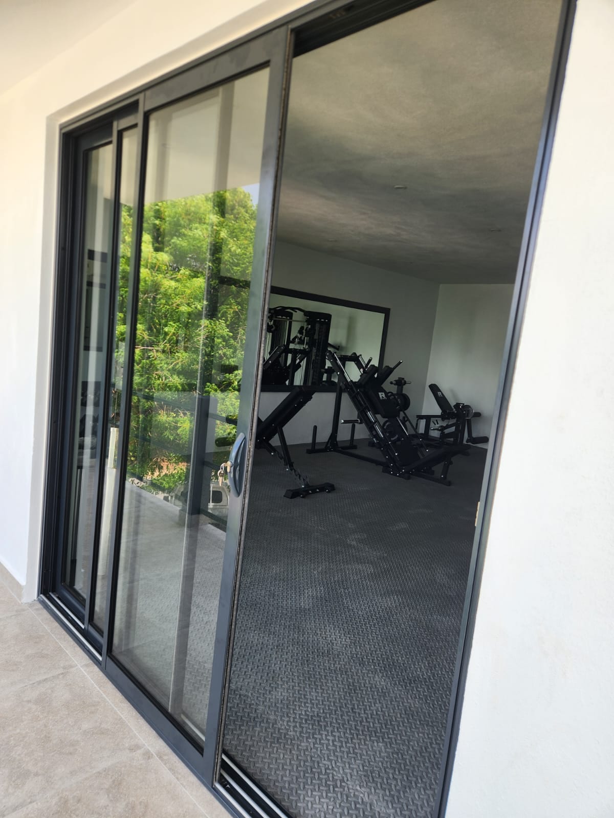 Black framed aluminium sliding glass door opening onto a private gym in Anguilla