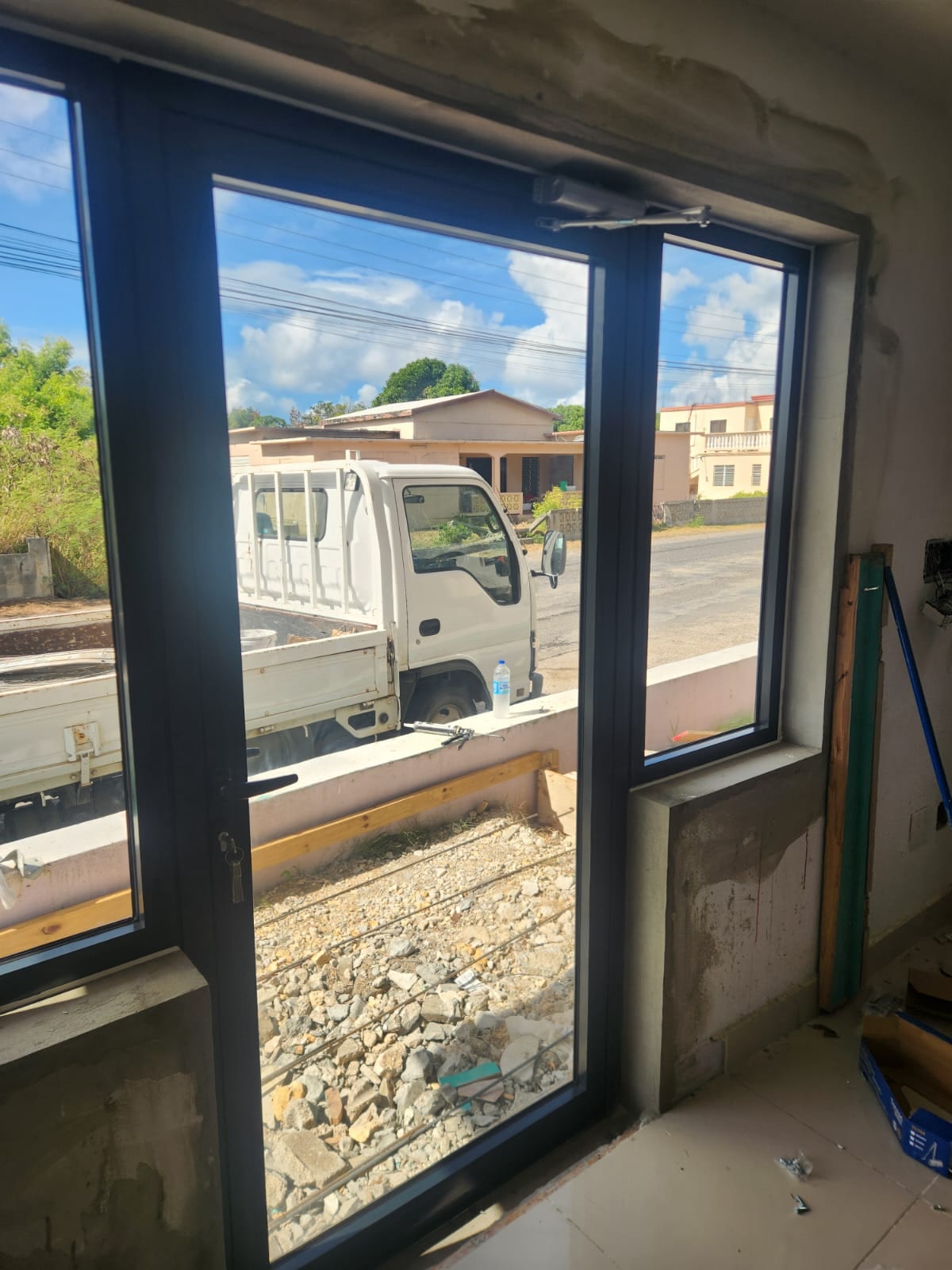 Interior view of a charcoal aluminium entry door and side window during installation in Anguilla