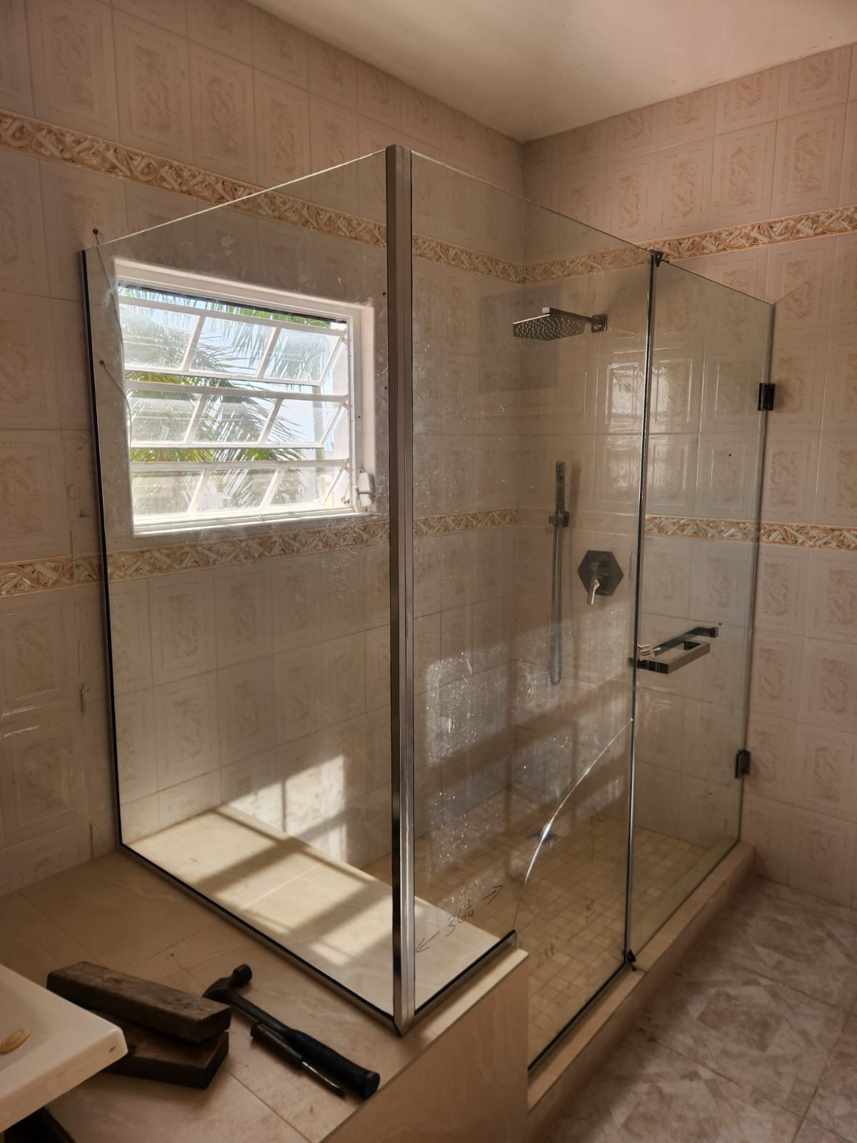 Newly installed glass shower enclosure with a polished chrome frame in a tiled bathroom in Anguilla