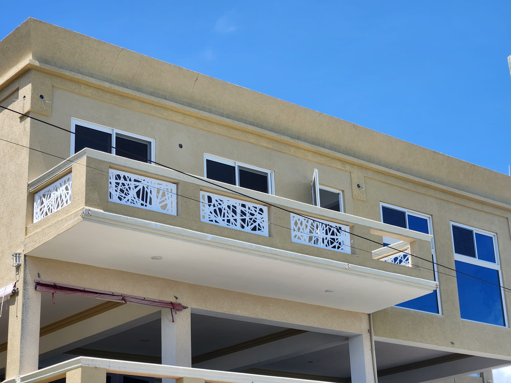Laser-cut aluminium balcony railing panels alongside white-framed sliding windows