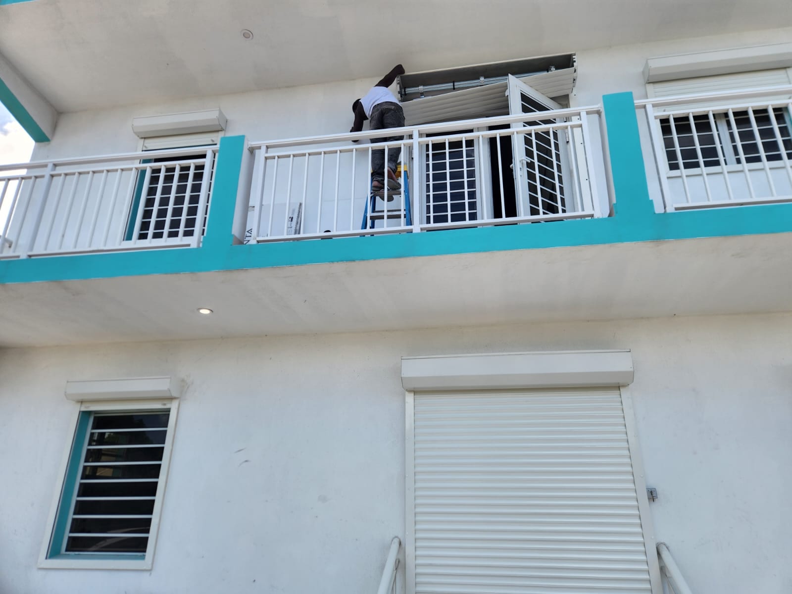 Fitting a white roller shutter above a balcony door on an apartment building in Anguilla
